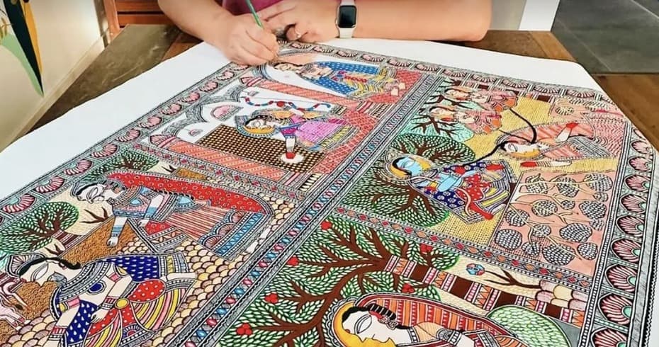 An artisan hand-drawing fine outline work on a large painted cloth